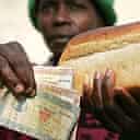 Zimbabwean woman holds bread and the money needed to buy it