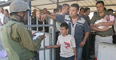 Palestinians wait for an Israeli soldier to check their identity cards at a checkpoint near the West Bank city of Nablus