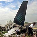 Rescue workers inspect the wreckage of a Garuda airlines Boeing 737-400 after it crashed at Adisucipto airport, Yogyakarta