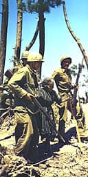 US troops take a civilian away from fighting in Okinawa in 1945