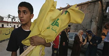 A boy carries Hizbullah flags