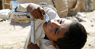 An Iraqi boy drinks from a tap at a camp for displaced people in Najaf