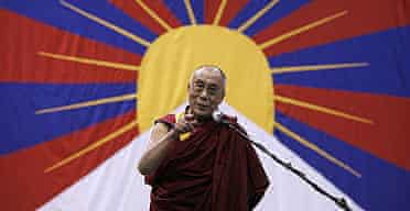Framed by the Tibetan flag, the Dalai Lama speaks to members of the Tibetan Community in New York.