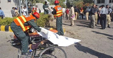 A rescue worker covers a dead body at the site of the suicide bombing in Rawalpindi