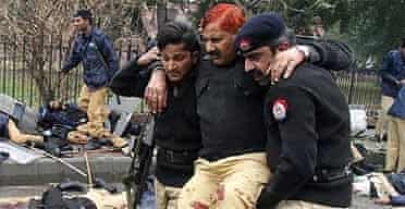Pakistani police help an injured colleague at the suicide attack site in Lahore