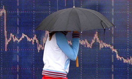 A woman walks past a screen showing trading market graphs in London on January 21, 2008