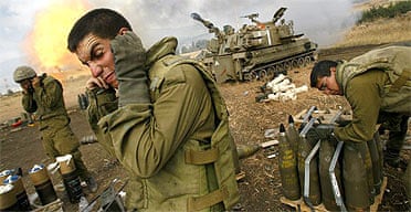 Israeli soldiers cover their ears as an artillery unit fires shells towards southern Lebanon