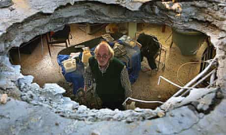 Silvio Grinberg peers through a hole in the ceiling of his living room caused by a Grad rocket fired by Palestinian militants from the Gaza Strip at the southern Israeli costal city of Ashkelon