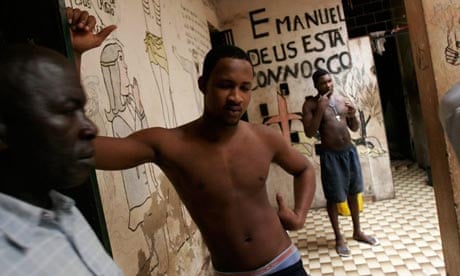  Police officer Sadio Corobo, left, walks past prisoners housed in the basement of a crumbling colonial villa in Bissau, Guinea-Bissau, July 17, 2007