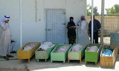 People gather at the Baquba hospital morgue next to caskets containing the bodies of six of their family members who were killed by a roadside bomb south of Baquba, Iraq