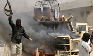 Mahdi Army fighters gesture as they stand next to a burning Iraq armored police vehicle