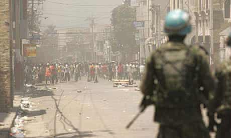 Haitian rioters block a street in downtown Port au Prince while Brazilian UN peacekeepers look on.