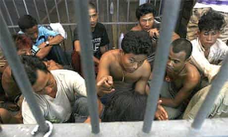 Burmese illegal migrant workers rescued from a cramped container sit in a prison cell at a police station in Ranong province, south of Bangkok