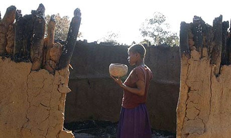 A woman recovers a pot from her destroyed hut after Zanu-PF militia attacked farms and burned workers from their homes