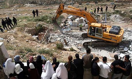 Palestinians watch an Israeli bulldozer destroying a Palestinian house in a village in the West Bank