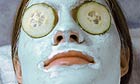 A woman recieving a spa treatment with a blue facial mask and cucumber slices on her eyes