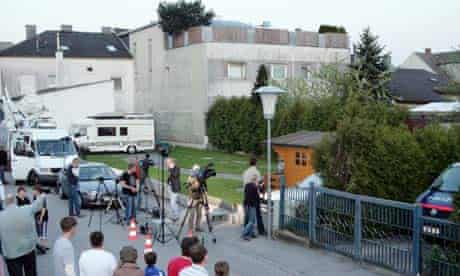 People watch at the back of a house where a 73-year-old man allegedly locked up his daughter in a basement for 24 years and fathered seven children with her, in Amstetten, Austria