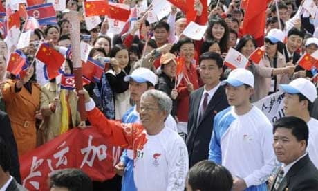  Former North Korean national soccer team player Pak Doo-ik carries the flame through Pyongyang