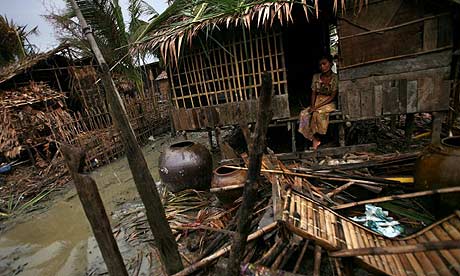 A woman sits outside her ruined home on the outskirts of Rangoon, Burma