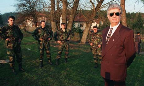 Former Bosnian Serb leader Radovan Karadzic stand surrounded by guards