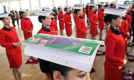 Chinese students balance books on their heads during an etiquette training class