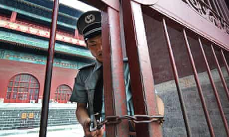 A Chinese security guard locks the gates at the Drum Tower in Beijing, following the murder of a US citizen at tourist attraction