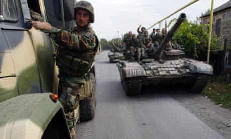 Georgian soldiers sit on a tank moving near the town of Tskhinvali