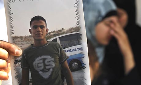 A relative of Qassem al-Mughrabi holds up a picture of the 19-year-old, whose car crashed into a patrol of Israeli soldiers