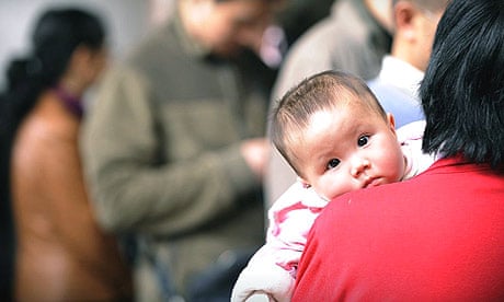A woman waits with her baby to be seen at a child hospital in Beijing