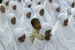 Gallery Eid al-Adha: Woman carries child Muslims pray