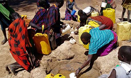 Ugandan women and children collect water from a hole dug in a dry riverbed at Kaabong village, Karamoja region