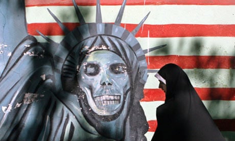 An Iranian walks past an American flag