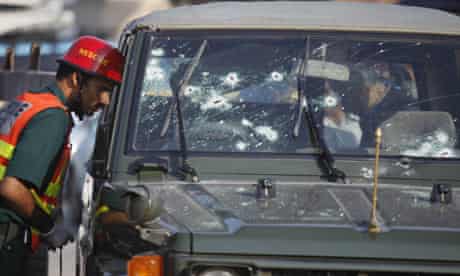 Emergency services examine an army jeep  after it was attacked by gunmen in Islamabad, Pakistan