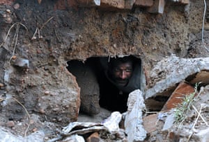 Flooding in India: A man looks through a hole in his home in Talmari, Karnataka