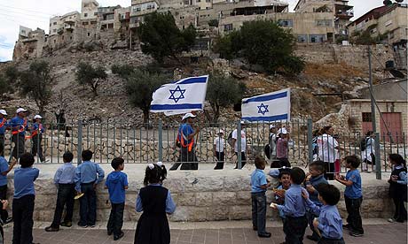 Palestinian children in a school courtyard as Israelis participating in a Sukkot celebration march