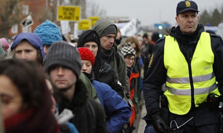 A police officer detains a climate activist after she sprayed