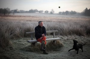 December weather: A man throws a ball to his dog while sitting on a bench in Richmond Park