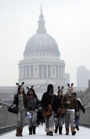 December snow: Young women wearing antler head bands walk over the Millennium Bridge