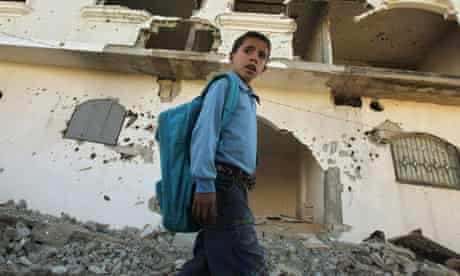 Palestinian boy walks past a damaged house in Beit Lahiya