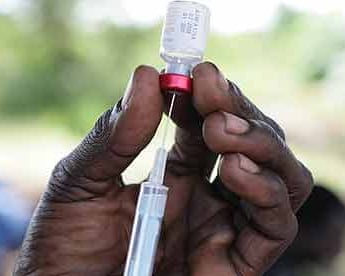 A community vaccinator prepares to inoculate young people in Katine