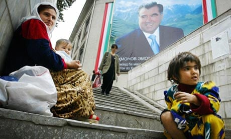A mother and her children beg in front of picture of a picture of Tajik President Emomali Rakhmonov