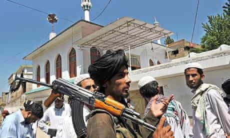 An armed Pakistani Taliban talks with residents outside a mosque in Buner