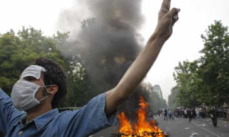 Supporter of Mir Hossein Mousavi in front of a burning police motorbike