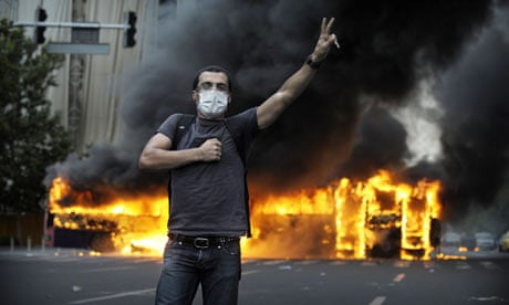 Smoke billows from a burning bus behind a supporter of Mir Hossein Mousavi 
