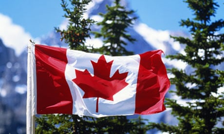 The Canadian flag with mountains and evergreens in background. 