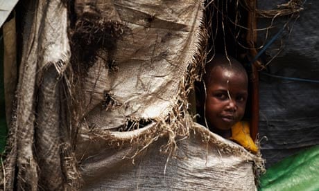 An internally displaced girl peers out of her home in the Mugunga camp in Congo