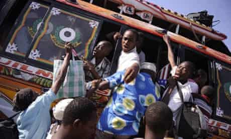 People climb onto departing buses in Port au Prince, Haiti