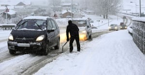 snow: Wetherby, Yorkshire: Traffic is  helped up a hill in heavy snow