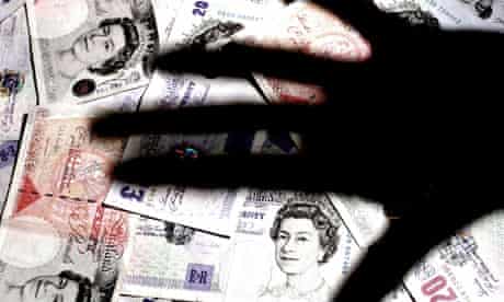 Shadow of hand over a pile of GBP banknotes