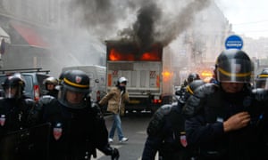 Riot police officers move back from a burning truck during clashes with youths in Lyon, France